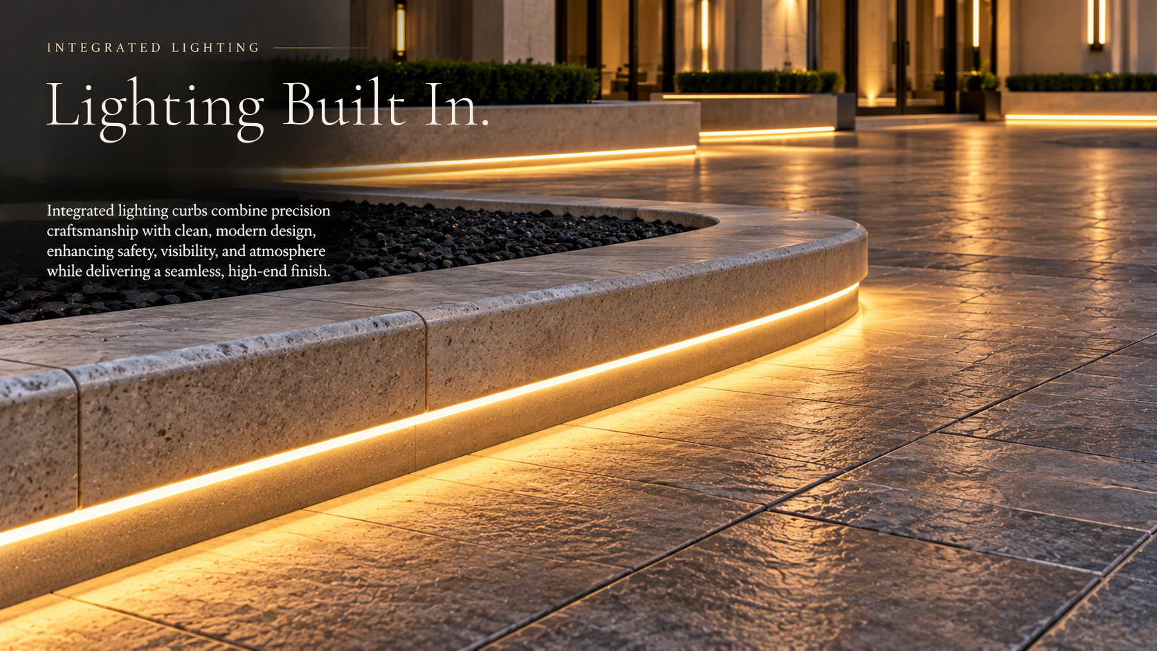 Illuminated concrete curbs and textured paving outside a building at night
